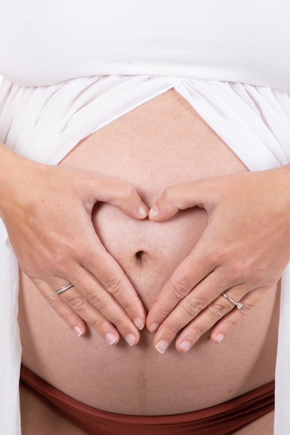 Pregnant woman body topless abdomen belly with hands finger in heart sign