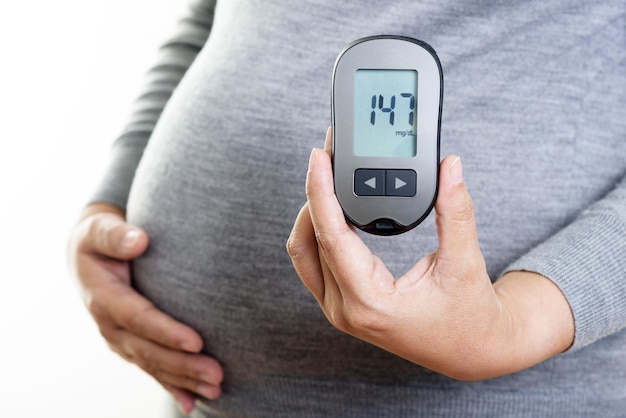 Pregnant woman checking blood sugar level with blood glucose meter Gestational diabetes