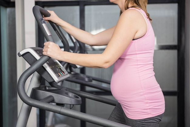 Pregnant woman on crosstrainer at the gym