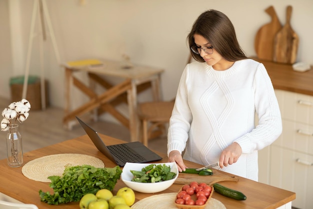 pregnant woman cutting vegetables in the kitchen