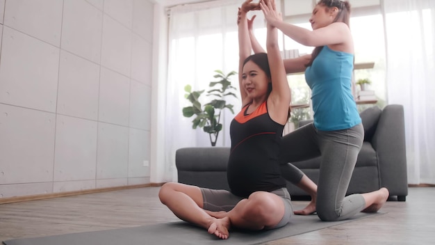 Pregnant woman doing pilates exercise with personal trainer at home.