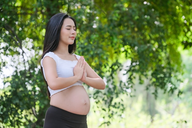 Pregnant woman doing yoga exercise in nature