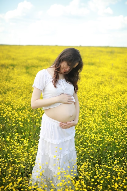 Pregnant woman in a dress in a field of flowers