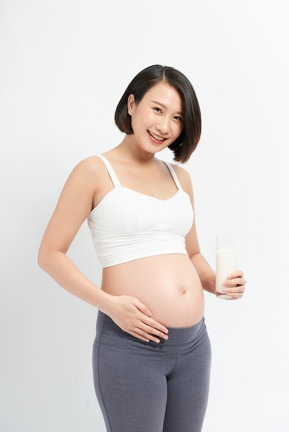 Pregnant woman drinking milk on the white background.