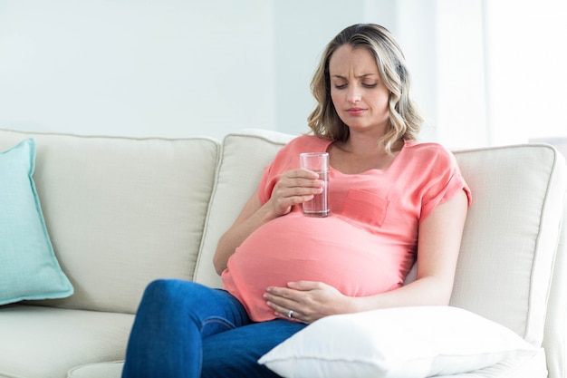 Pregnant woman drinking water in the living room