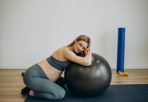 Pregnant woman exercising with fit ball on a class of pilates