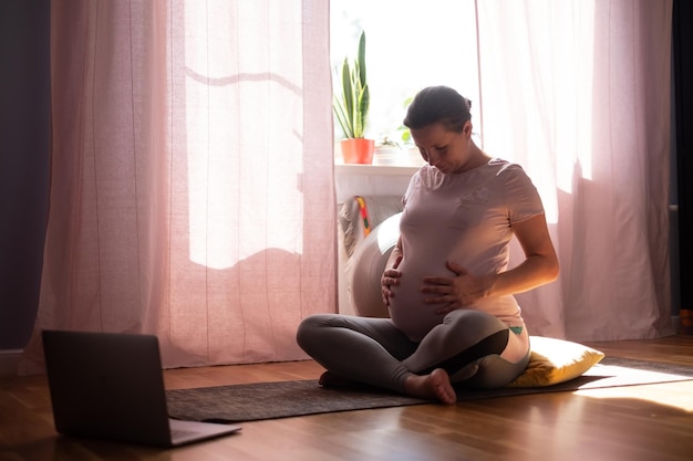 Pregnant woman on fitness mat training at home