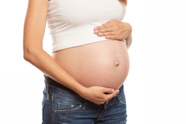 The pregnant woman gently touches her big belly. Waiting for a miracle. Close-up. Isolated