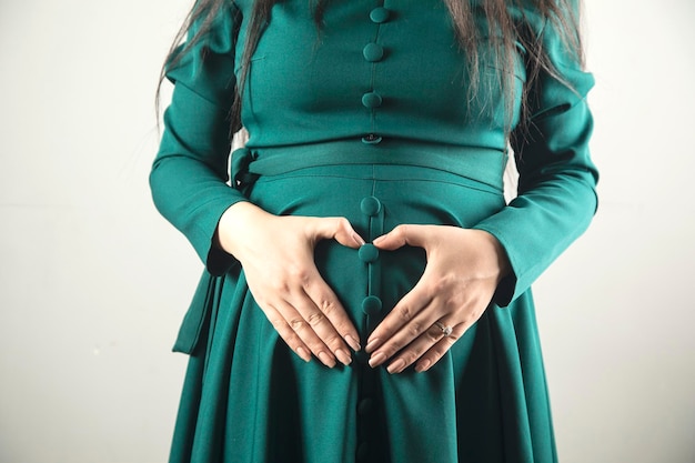 Pregnant woman hand heart sign on the belly