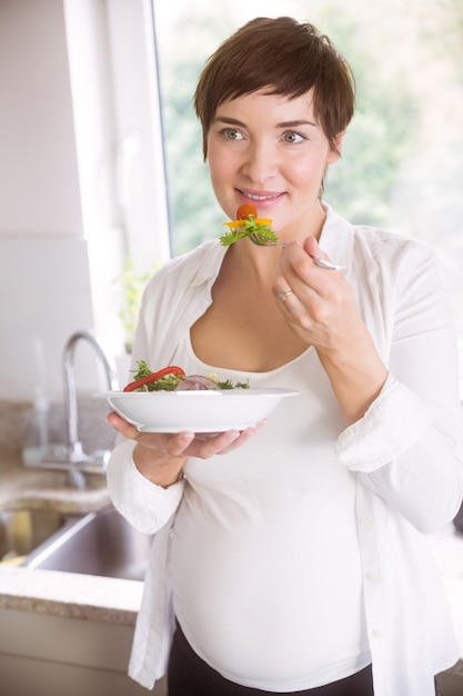 Pregnant woman having bowl of salad