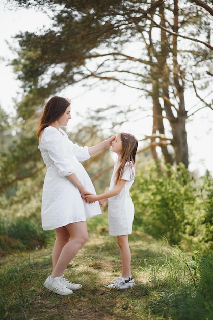 Pregnant woman and her daughter in the park at sunset A happy family