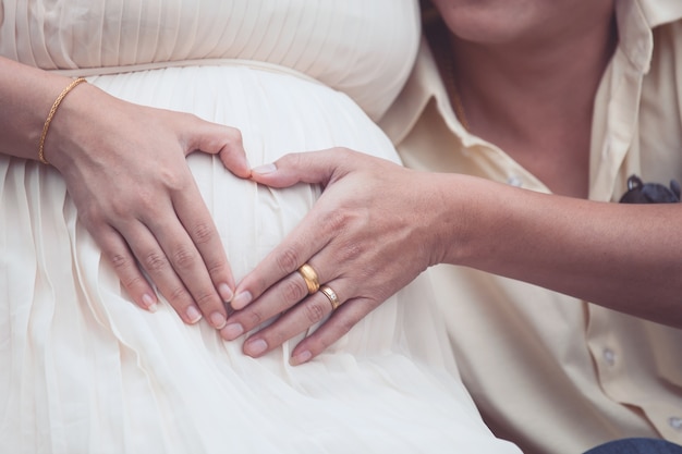 Pregnant woman and her husband making hand heart shape