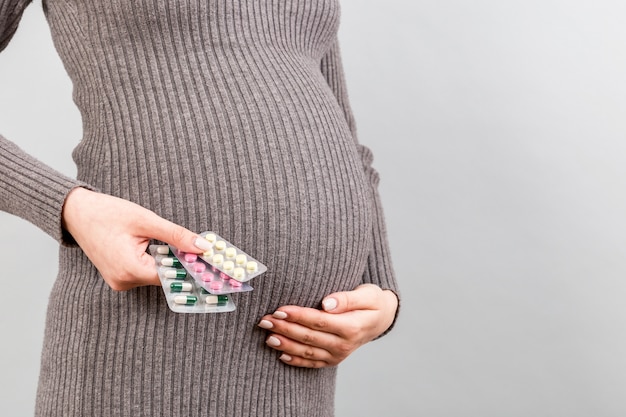 Pregnant woman holding pill blisters