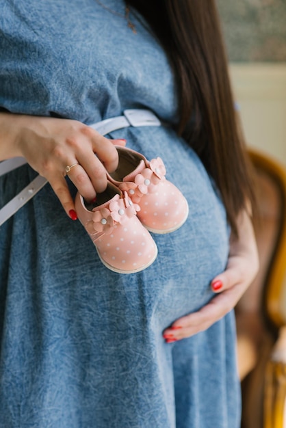 Pregnant Woman Holding Pink Baby Shoes keeps her waiting for the birth of her daughter.