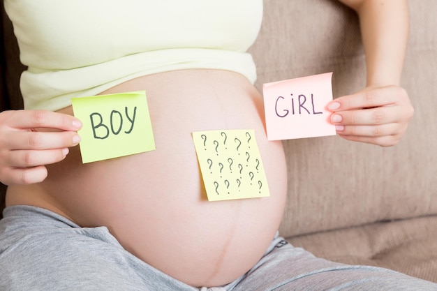 Pregnant woman holding square multicolored stickers with question marks