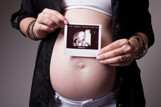 Pregnant woman holding a ultrasound on her belly