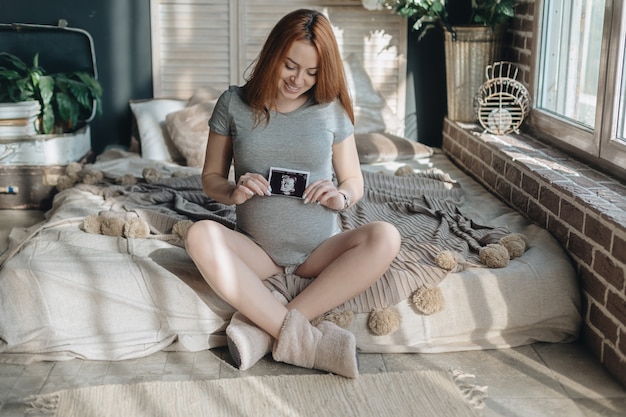 Pregnant woman holding ultrasound scan of baby