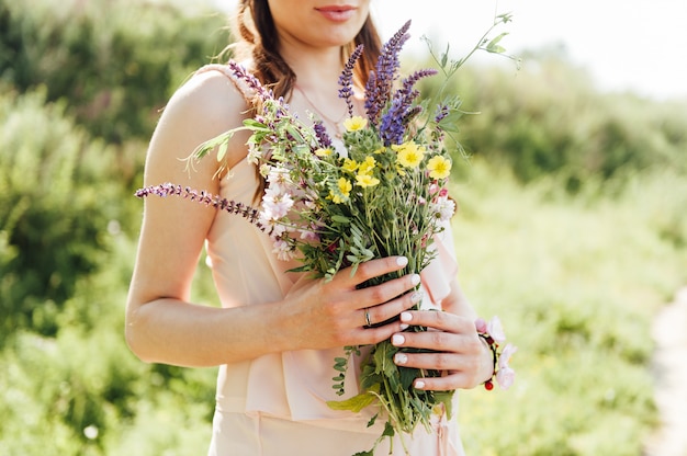 Pregnant woman holding wildflowers at the park