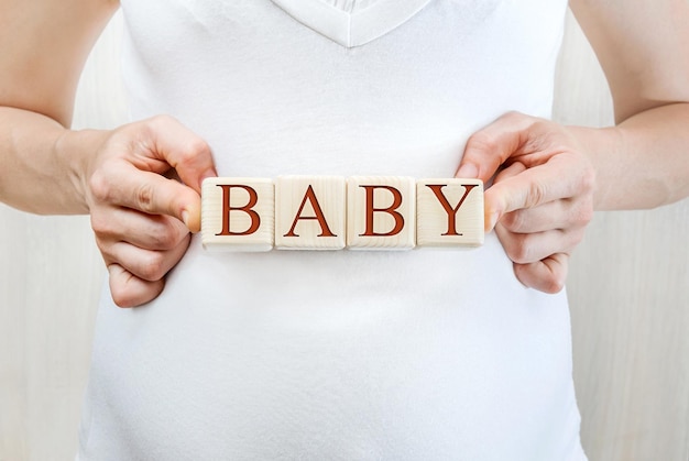 Pregnant woman holding wooden cubes with word Baby