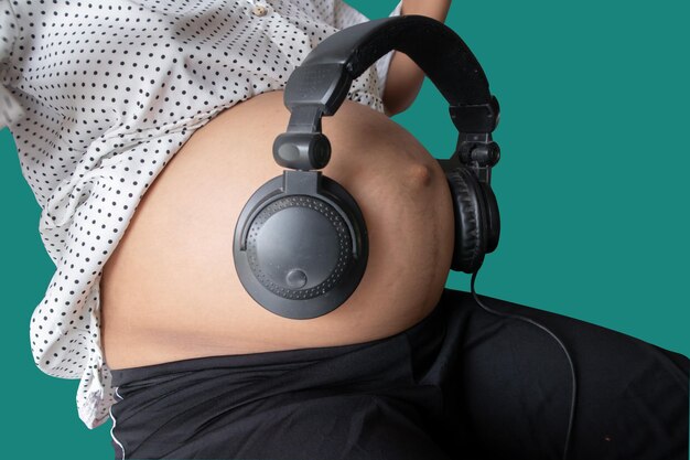 Pregnant woman holds headphones to her stomach