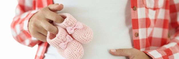 Pregnant woman holds pink slippers for newborn pregnancy concept