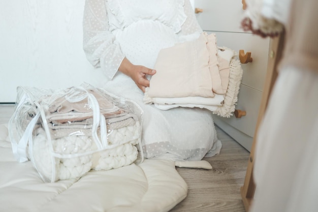 Pregnant woman is getting ready for the maternity hospital packing baby stuff pregnant woman preparing and planning baby clothes