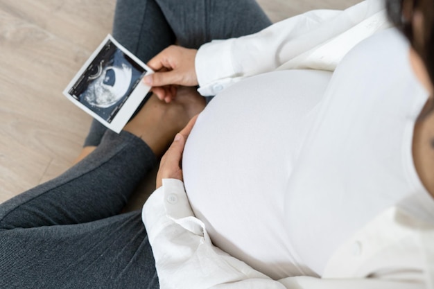 A pregnant woman is happily watching the fetal ultrasound in the house