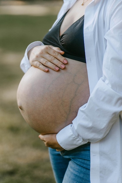 Photo a pregnant woman is holding her belly close up