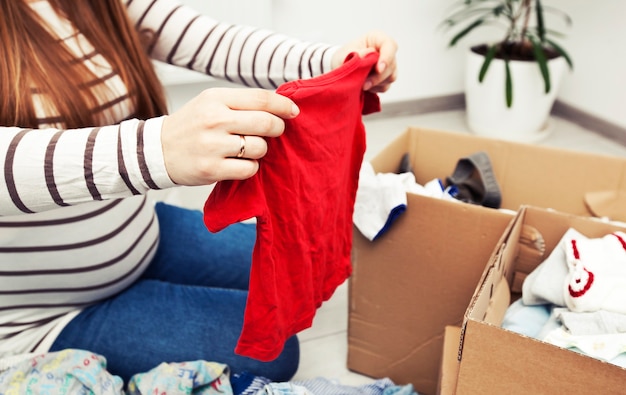 The pregnant woman is sorting baby clothes