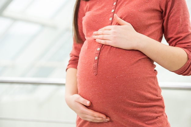 Pregnant woman is touching her belly.