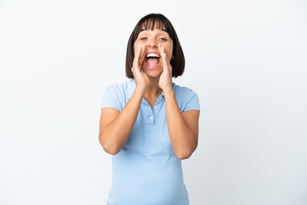 Pregnant woman over isolated white background shouting and announcing something