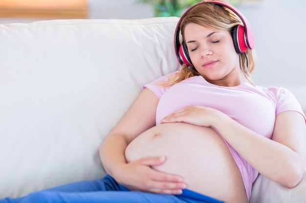 Pregnant woman listening music and touching her belly