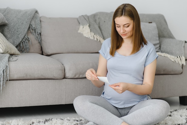 Pregnant woman looking at her baby sonography. Happy expectant lady enjoying first photo of her unborn child, anticipating her future life, copy space