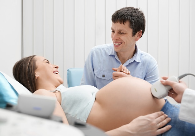 Pregnant woman and man on ultrasound exam in hospital.