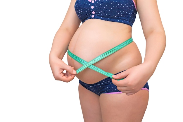 Pregnant woman measures her stomach with a measuring tape