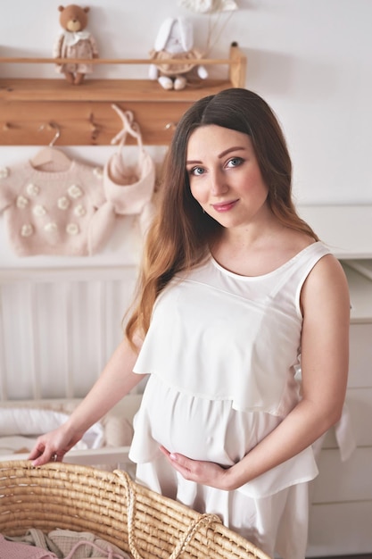 Pregnant woman in nursery Preparation for childbirth Babies wear and accessories