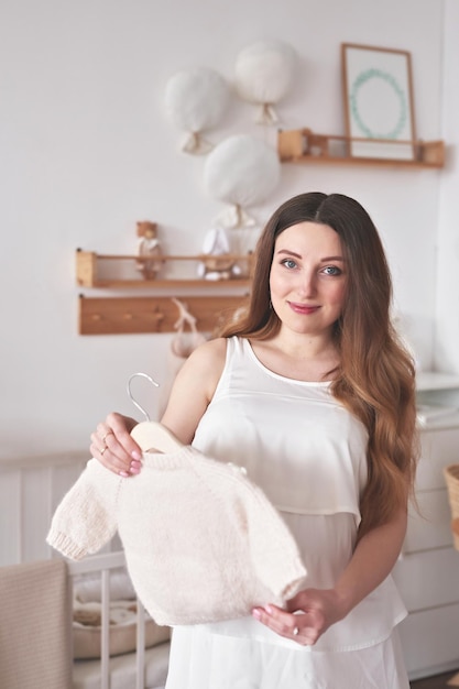 Pregnant woman in nursery Preparation for childbirth Babies wear and accessories