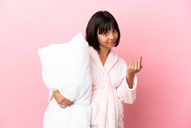 Pregnant woman in pajamas isolated on pink background doing coming gesture