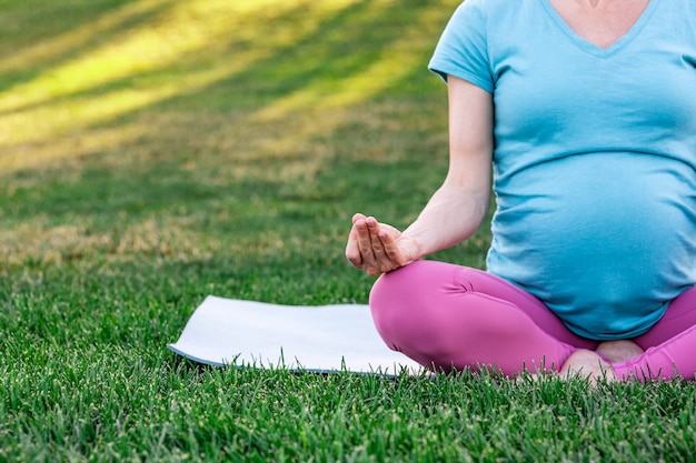 Pregnant woman practicing yoga in nature, meditation and relaxation outdoor