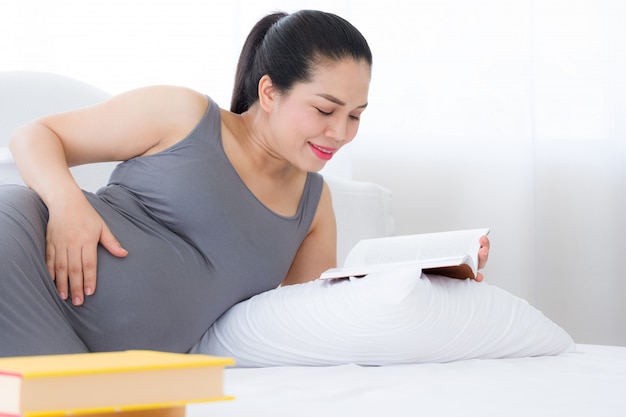 Pregnant woman reading a book and put your hand on belly. Mental health care and pregnancy.