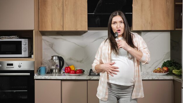 Pregnant woman sings with spoon imitating microphone dances