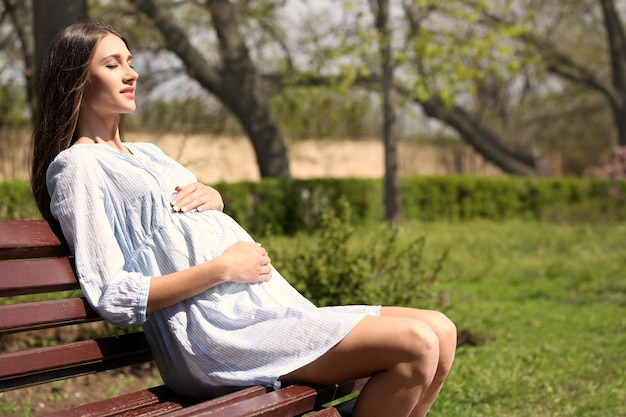 Pregnant woman sitting on chair in park