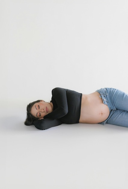 Photo a pregnant woman standing next to the window with hands on her belly