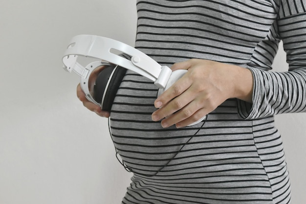 Pregnant woman touching Headphones on her belly.