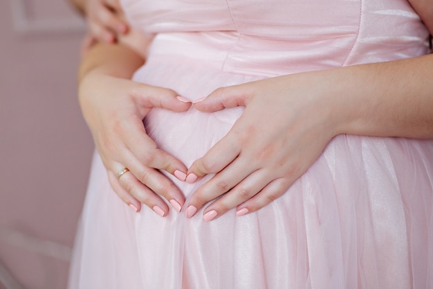 Pregnant woman touching her belly close up