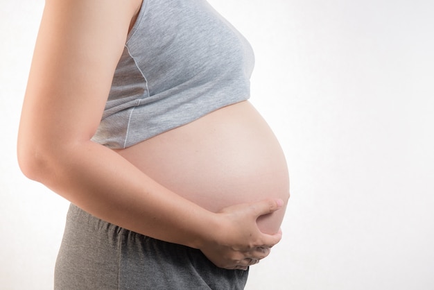 pregnant woman touching her belly on white background