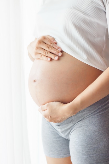 pregnant woman touching her belly with hands. 