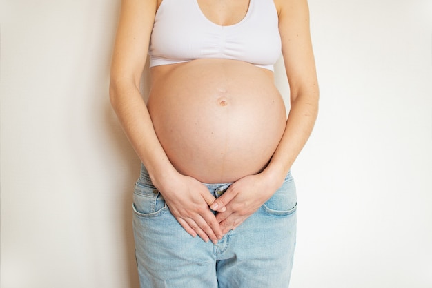 Pregnant woman with abdominal pain. He holds his stomach in pain with his hands. Illness during pregnancy.