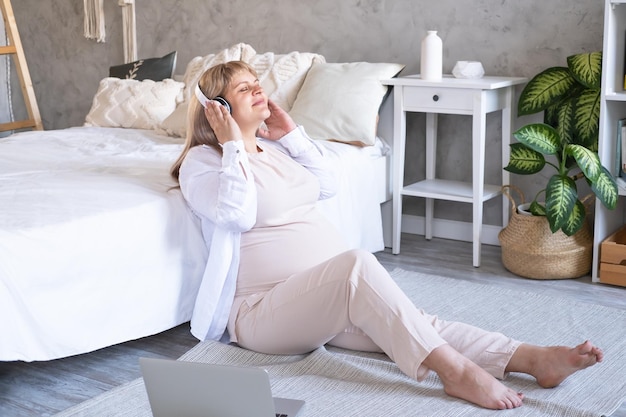 pregnant woman with big belly advanced pregnancy in wireless headphone listening music