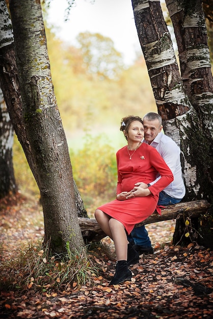 Pregnant woman with her husband in the autumn park